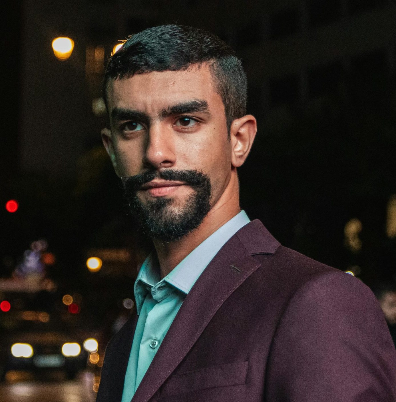 Confident man in a classic suit stands on a vibrant city street at night. Urban nightlife ambiance.